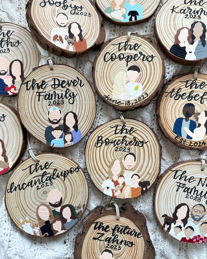 May include: A collection of 10 round wooden ornaments with painted family portraits and names. Each ornament features a different family name, a year, and a painted portrait of the family members. The ornaments are painted in various colors, including brown, black, white, red, blue, and yellow.