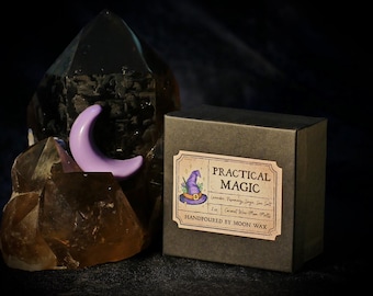 May include: A dark brown box with a label that reads "Practical Magic" next to a purple crescent moon and a large dark crystal. The label features a witch's hat illustration and ingredient list. The box is handpoured with Moon Wax.