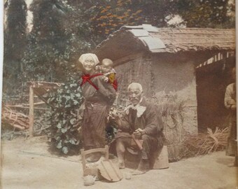 Japanese Meiji Era Albumen Hand Colored Photograph Print Japanese Peasant Couple w Baby Taking Tea in a Garden Setting Kizuru Smoking Pipe
