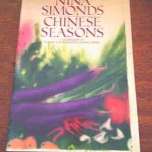 May include: A cookbook titled "NINA SIMONDS CHINESE SEASONS" with a colorful cover featuring vegetables. The cover art includes purple eggplants, red chili peppers, and green vegetables. The subtitle reads "A CELEBRATION OF CLASSIC AND INNOVATIVE CHINESE DISHES."
