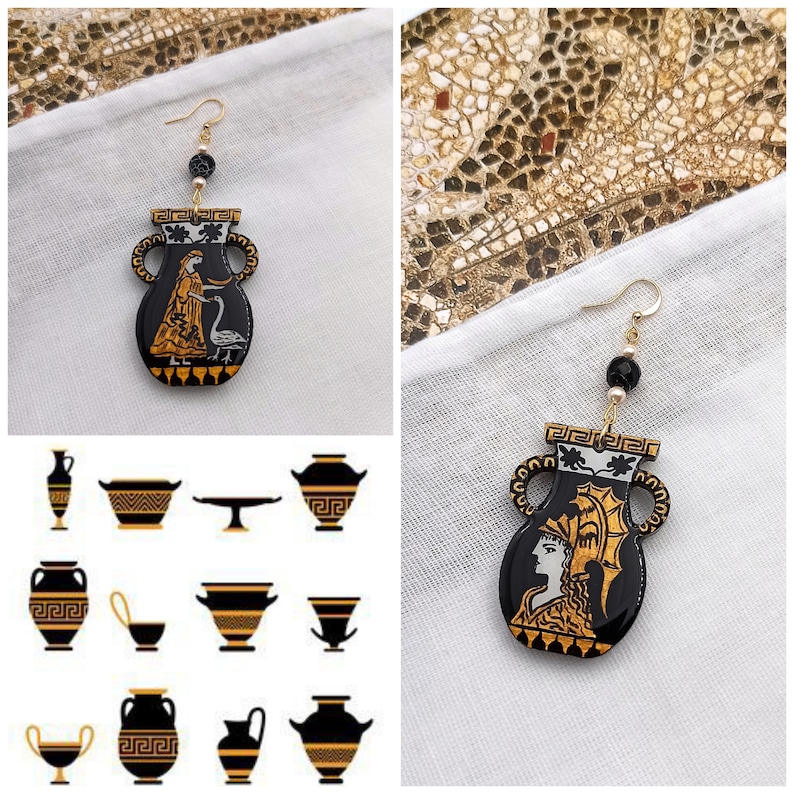 May include: A pair of gold earrings with black and white ceramic pendants shaped like ancient Greek vases. The vases feature a gold design and a woman holding a bird.