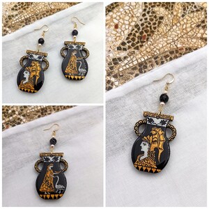 May include: A pair of black and gold earrings with a design of a woman in a vase. The earrings are made of resin and have a gold-tone finish.