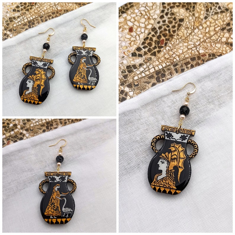May include: A pair of black and gold earrings with a design of a woman in a vase. The earrings are made of resin and have a gold-tone finish.