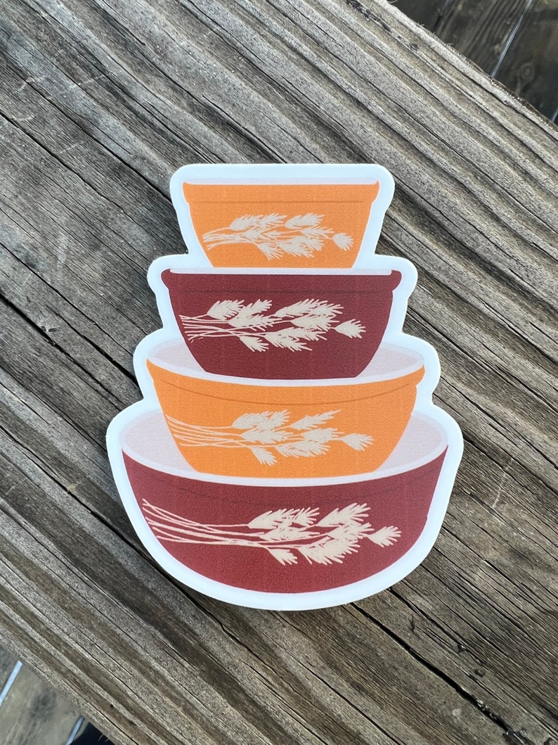 May include: A set of four nesting bowls with a wheat design. The bowls are in shades of brown and orange.