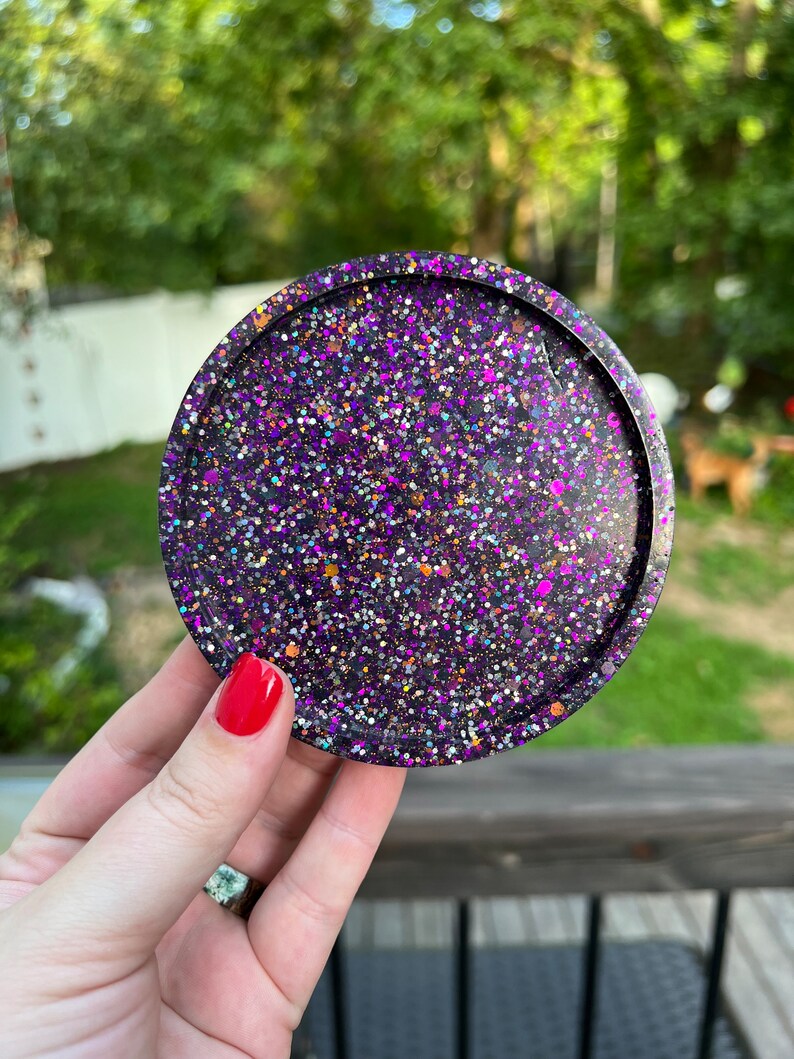 May include: A round, purple and black glitter coaster with a black border.