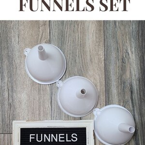 May include: Set of three white plastic funnels, labelled "FUNNELS" on a black letter board. Sensory funnels for children.