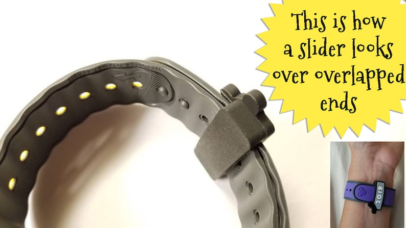 K&ouml;nnte beinhalten: Nahaufnahme eines grauen, verstellbaren Armbands mit einem Schiebermechanismus. Das Band hat gelbe Akzente und ein kleines Logo auf der Innenseite. Der Schieber ist so konzipiert, dass er die Enden des Bandes &uuml;berlappt, um einen sicheren Sitz zu gew&auml;hrleisten.