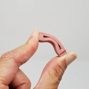 K&ouml;nnte beinhalten: Eine rosa Nasenklammer aus Kunststoff zum Schwimmen. Die Klammer ist so konzipiert, dass sie beim Schwimmen hilft, Wasser aus der Nase fernzuhalten.