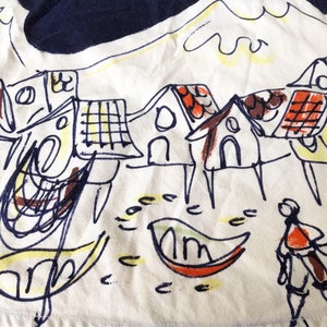 May include: A white fabric with a hand-drawn illustration of a village with houses, a boat, and a person. The houses are drawn in black and brown with red and yellow accents. The boat is drawn in orange and green. The person is drawn in black and orange.