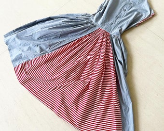 May include: A blue and red striped dress with a gathered skirt. The dress has a sleeveless bodice and a button closure in the back.