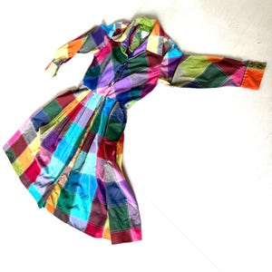 May include: A colorful plaid dress with long sleeves and a button-up front. The dress has a fitted bodice and a full skirt.