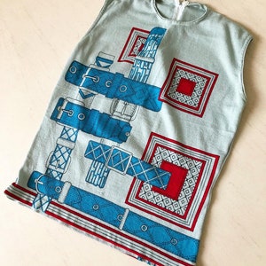 May include: A sleeveless light blue top with a blue and red print of belts and squares.