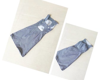 May include: A gray sleeveless dress with a cutout detail in the back. The dress is laid flat on a light wood surface.