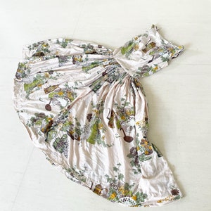 Puede incluir: Un vestido rosa sin mangas con estampado floral que presenta hojas verdes, ramas marrones y flores amarillas. El vestido tiene una cintura fruncida y una falda completa.