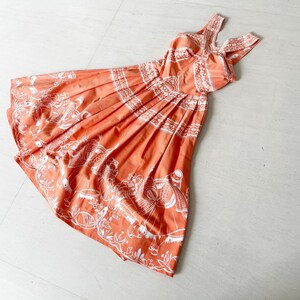 May include: A sleeveless orange dress with a white print of stylized figures. The dress has a fitted bodice and a full skirt.