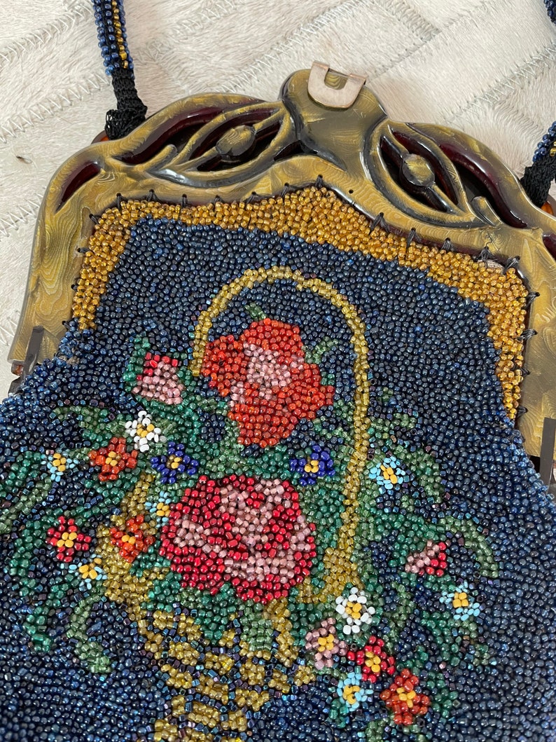 May include: A vintage beaded purse with a floral design. The purse is made of blue, green, red, and yellow beads. The purse has a gold-colored metal frame and a clasp.