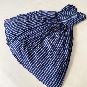 May include: A strapless dress with a blue and purple striped pattern. The dress is made of a lightweight fabric and has a gathered skirt.