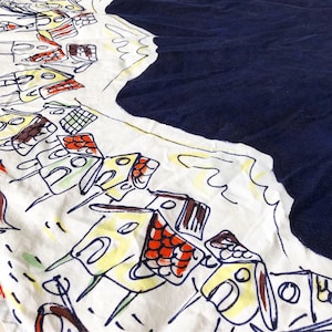 May include: A white fabric with a blue border and a repeating pattern of yellow, red, and blue houses. The houses are drawn in a simple, childlike style.