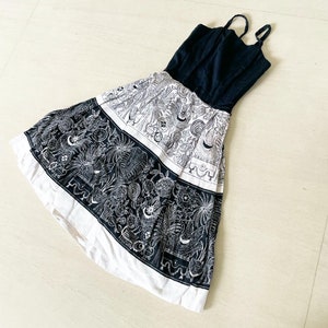 May include: A black and white sundress with a floral print. The dress has a fitted bodice and a full skirt.
