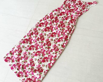 May include: A white maxi dress with a pink floral print. The dress has a scoop neck and thin straps.