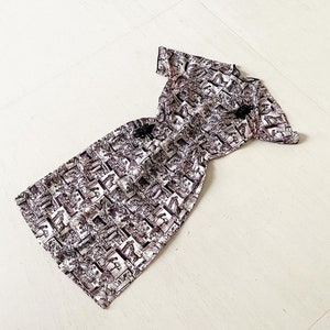 Könnte beinhalten: Ein weißes Kleid mit schwarzen Mustern und kurzen Ärmeln. Das Kleid hat einen figurbetonten Oberteil und einen fließenden Rock.