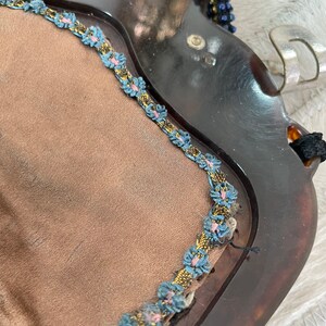May include: A vintage tortoiseshell compact mirror with a blue and gold trim. The mirror has a brown velvet lining.