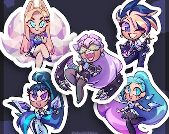May include: A collection of KDA All Out stickers featuring stylized illustrations of the characters. Each sticker showcases a different character in vibrant colors, with dynamic poses and unique outfits. The stickers have a white border.