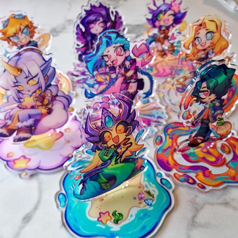 May include: A selection of vibrant acrylic charms depicting cartoon characters. Each charm showcases a unique design with bright colours and intricate details. The charms are displayed on a white surface, highlighting their playful and artistic style.