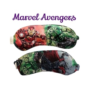 Puede incluir: Dos antifaces para dormir con personajes de Marvel Avengers. Uno muestra a Iron Man y Hulk, el otro a Hulk y Capitán América. El texto "Marvel Avengers" está escrito en púrpura encima de los antifaces.