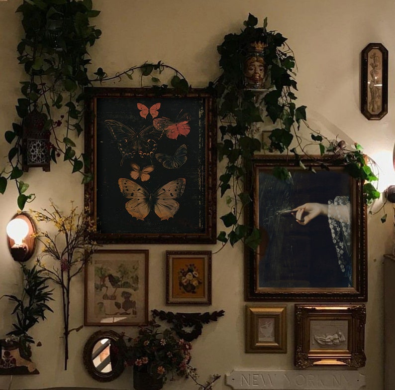 May include: A wall gallery featuring a variety of framed artwork, including a vintage butterfly illustration, a painting of a hand holding a feather, and a framed print of a floral design. The wall is decorated with greenery and a small mirror.