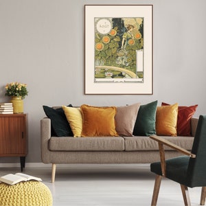 Puede incluir: Un p&oacute;ster vintage enmarcado con una mujer con un vestido verde de pie en un jard&iacute;n con girasoles y un estanque. El p&oacute;ster est&aacute; titulado "AOUT" y est&aacute; colgado en una pared gris sobre un sof&aacute; marr&oacute;n con almohadas de varios colores.