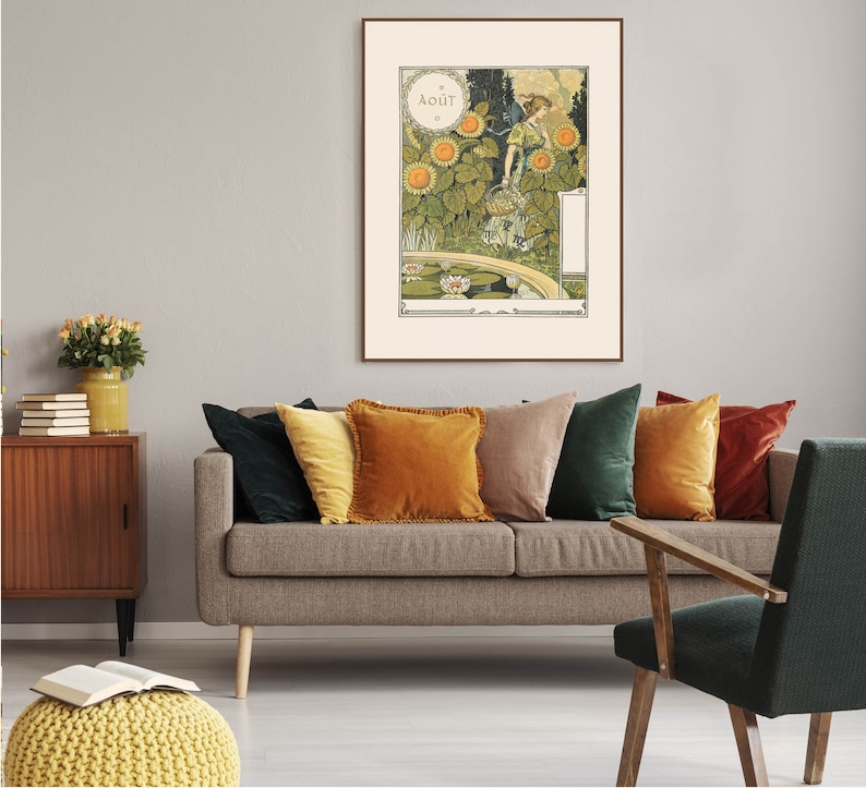 Puede incluir: Un p&oacute;ster vintage enmarcado con una mujer con un vestido verde de pie en un jard&iacute;n con girasoles y un estanque. El p&oacute;ster est&aacute; titulado "AOUT" y est&aacute; colgado en una pared gris sobre un sof&aacute; marr&oacute;n con almohadas de varios colores.