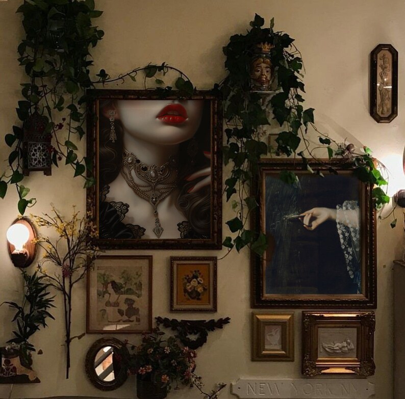 Puede incluir: Una galer&iacute;a de pared con una variedad de obras de arte enmarcadas, que incluyen un retrato de una mujer con labios rojos, una pintura de una mano sosteniendo una pluma y una impresi&oacute;n floral. La pared est&aacute; decorada con vegetaci&oacute;n y una peque&ntilde;a l&aacute;mpara.