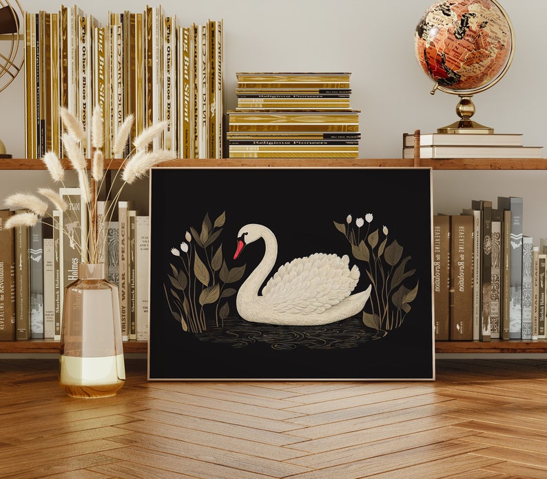 May include: A black and gold framed print of a white swan with a red beak, swimming in a pond with green and gold foliage. The print is on a shelf with books and a globe.