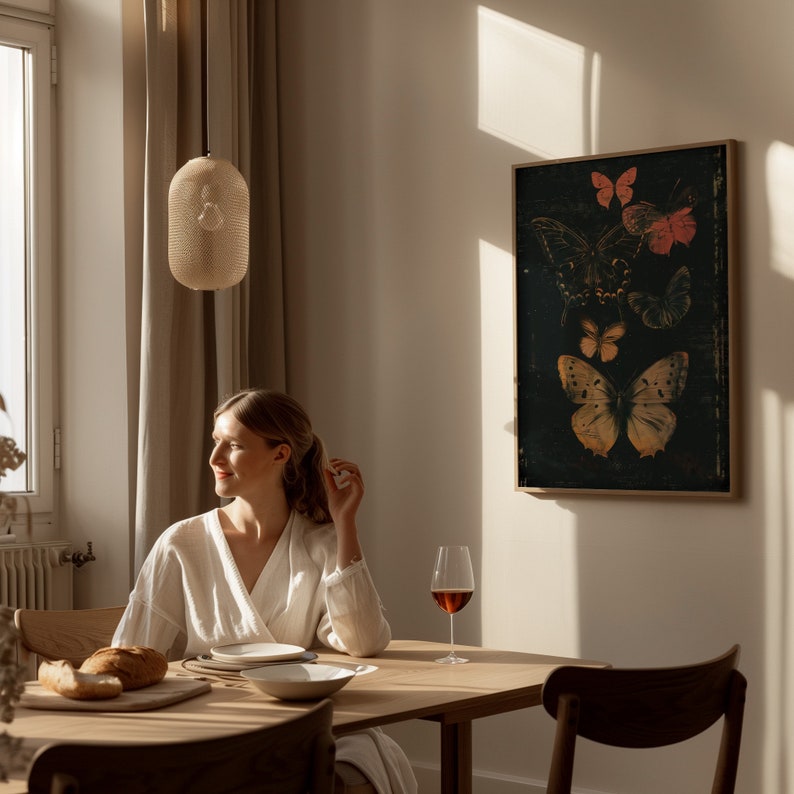 May include: A woman sits at a wooden table with a glass of red wine. The table is set with a plate and a bowl. There is a basket of bread on the table. A framed print of butterflies hangs on the wall behind the woman.