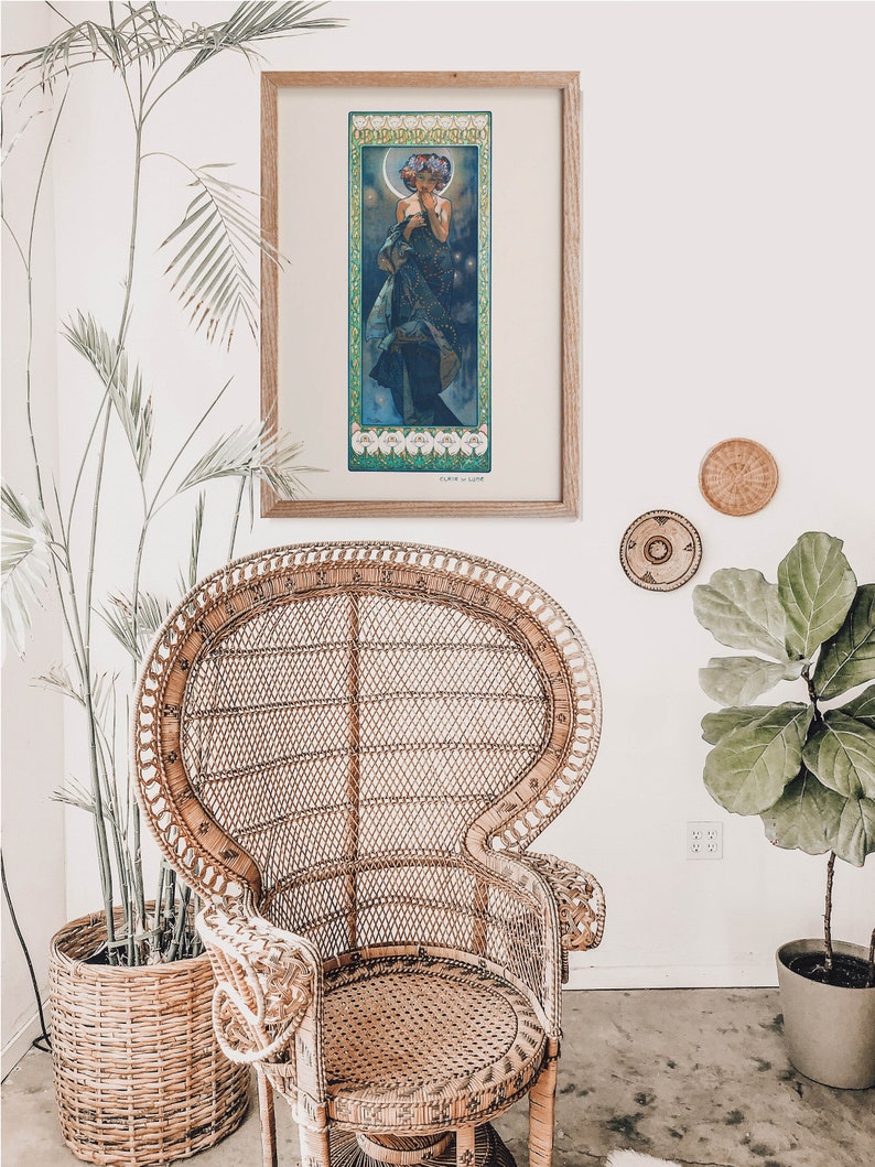 Puede incluir: Una impresi&oacute;n de arte vintage enmarcada de una mujer con un vestido azul fluido y una corona de flores. La impresi&oacute;n est&aacute; en un marco de madera y est&aacute; colgada en una pared blanca.