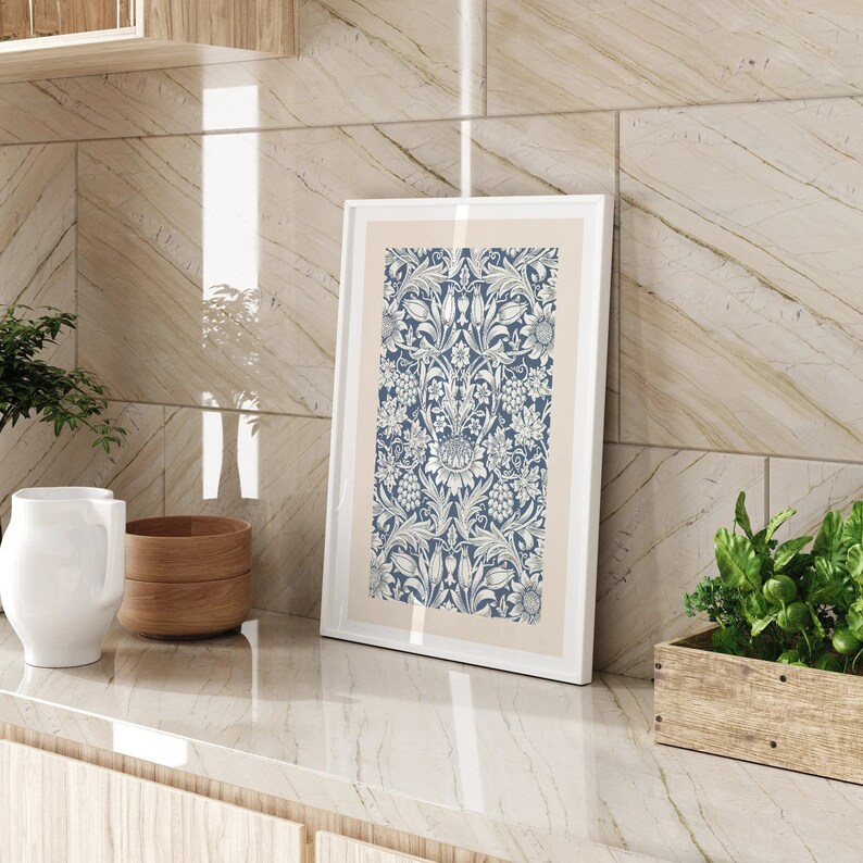 May include: A white framed print with a blue and white floral pattern. The print is hanging on a light brown tiled wall.