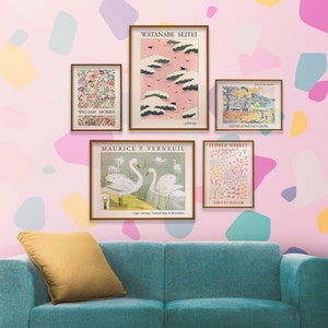 May include: Five framed art prints with various designs, including a pink sky with clouds, a flower market, swans, and a floral pattern. The prints are hanging on a pink wall with a teal couch in the foreground.
