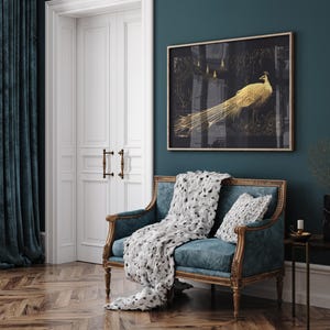 Puede incluir: Un sof&aacute; de terciopelo azul turquesa con una manta de tiro con estampado blanco y negro y una almohada blanca. Un cuadro dorado con un pavo real dorado sobre fondo negro cuelga de la pared detr&aacute;s del sof&aacute;.