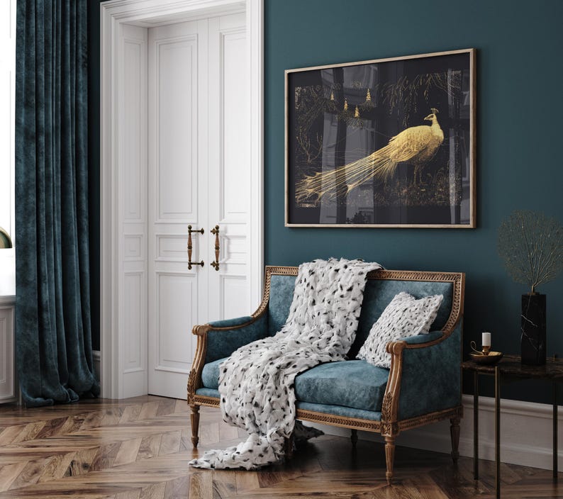 Puede incluir: Un sof&aacute; de terciopelo azul turquesa con una manta de tiro con estampado blanco y negro y una almohada blanca. Un cuadro dorado con un pavo real dorado sobre fondo negro cuelga de la pared detr&aacute;s del sof&aacute;.
