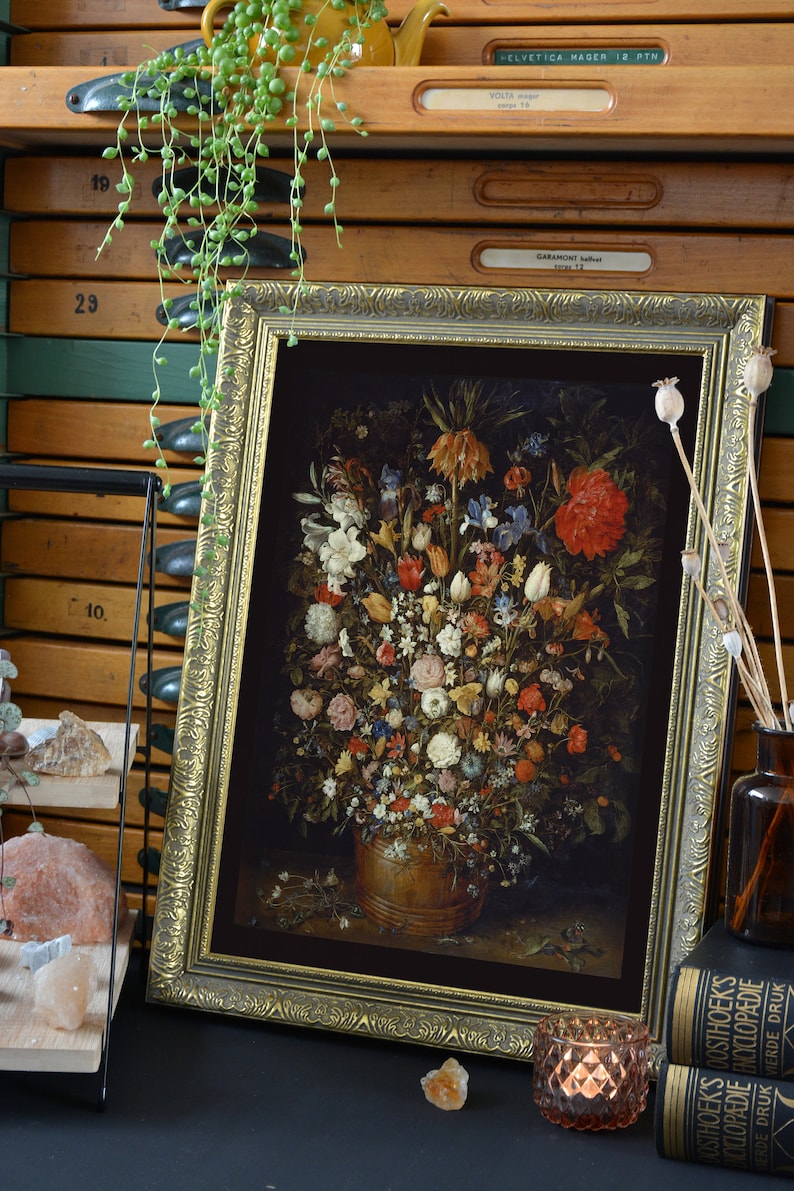 Peut inclure: Une impression encadr&eacute;e d'une nature morte repr&eacute;sentant un vase rempli d'un assortiment de fleurs color&eacute;es. Les fleurs sont dispos&eacute;es de mani&egrave;re sym&eacute;trique et comprennent des roses, des tulipes et des lys. Le vase est de couleur brun fonc&eacute; et repose sur un fond sombre.