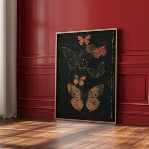 May include: A framed print of a black background with a collection of butterflies in various shades of brown, orange, and pink. The butterflies are arranged in a cluster, with some overlapping.