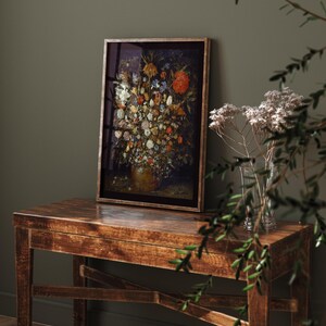 Peut inclure: Une impression encadr&eacute;e d'une nature morte repr&eacute;sentant un vase rempli de fleurs color&eacute;es. Le vase est brun et l'arri&egrave;re-plan est sombre.