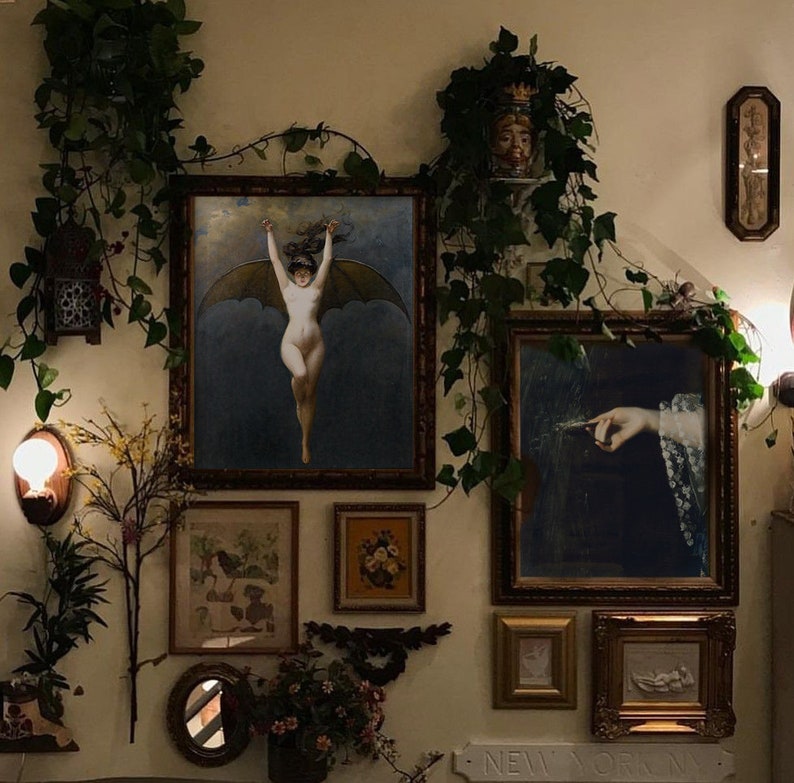 Op de afbeelding: Een wandgalerij met verschillende ingelijste kunstwerken, waaronder een schilderij van een vrouw met vleugels, een schilderij van een hand en een ingelijste print van bloemen. De muur is versierd met groen en een klein lampje.