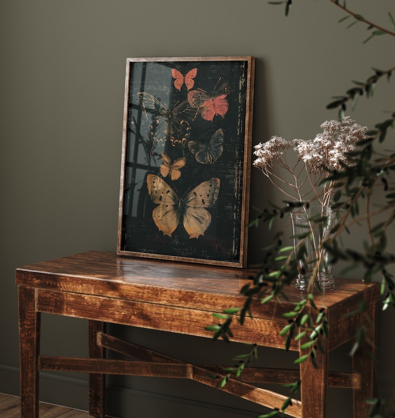 May include: A framed print of a dark background with five butterflies in various shades of orange, yellow, red, and blue. The butterflies are arranged in a vertical pattern, with the largest butterfly at the bottom.