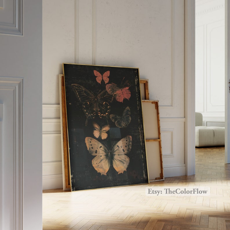 May include: A black canvas print with a gold frame features a vintage illustration of butterflies in shades of pink, orange, and yellow. The butterflies are arranged in a cluster on a dark background.