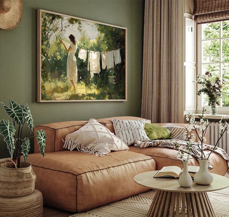 Puede incluir: Un sof&aacute; seccional de cuero marr&oacute;n con almohadas de patrones blancos y negros, una almohada de tiro verde y una manta de tiro blanca. El sof&aacute; est&aacute; en una sala de estar con una pintura de una mujer colgada en la pared, una ventana con cortinas blancas y una mesa de caf&eacute; de madera con un libro y dos jarrones.