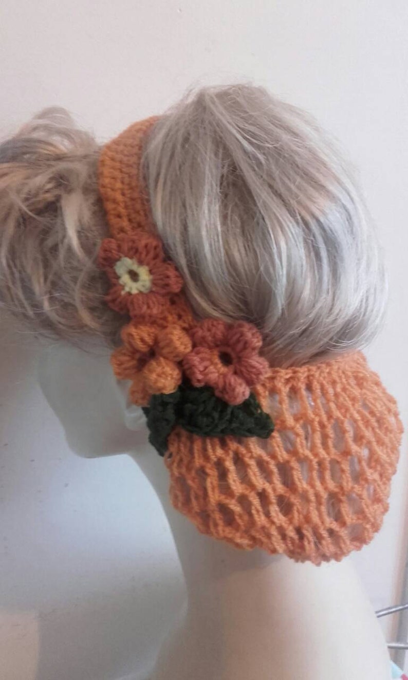 May include: A crocheted hairnet with a floral design in shades of orange and green. The hairnet is made with a delicate open weave pattern.
