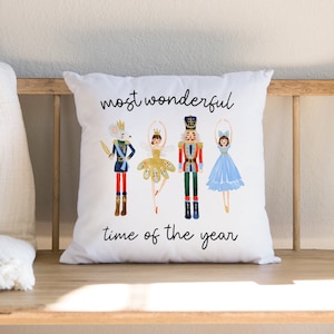 May include: White throw pillow with a colorful illustration of characters from the Nutcracker ballet. The text "most wonderful time of the year" is printed below the illustration.