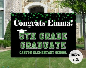 Puede incluir: Un letrero de jardín negro de graduación con el texto "¡Felicidades Emma!" y "5th Grade Graduate" en letras blancas y verdes brillantes. El letrero mide 45,7x61 cm e incluye el nombre de la escuela. El letrero se muestra en un césped verde.